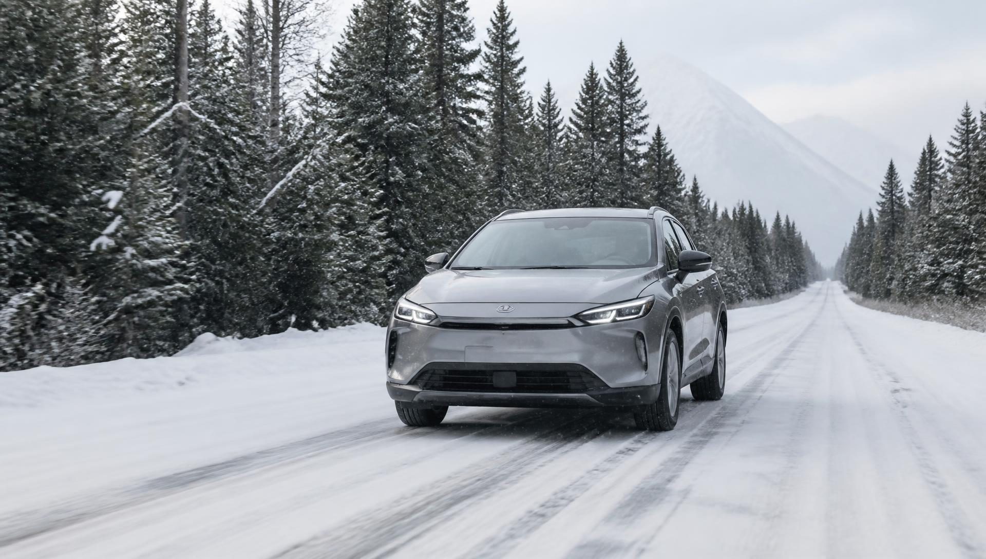 Silver hybrid SUV driving on a snow-covered forest road during light snowfall in winter